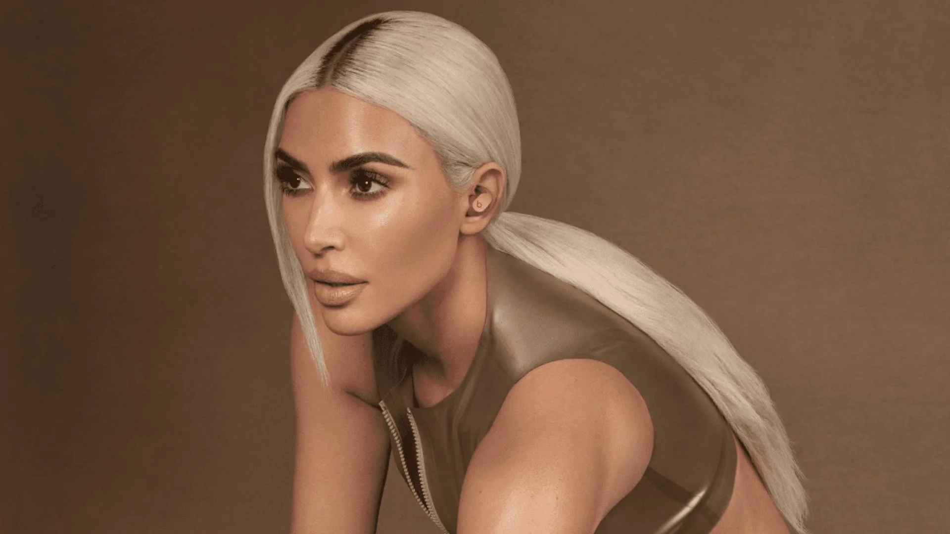 Stylish woman with platinum blonde hair in a sleek ponytail wearing a metallic top, showcasing a bold, futuristic beauty look against a warm-toned background.